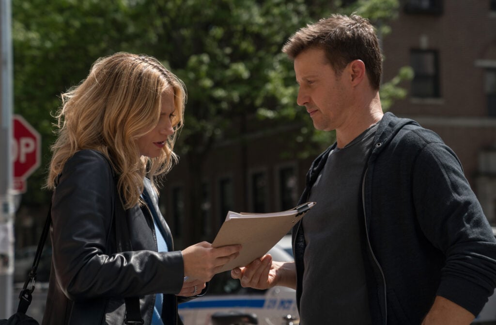 Eddie stares at a file folder Jamie gives her on Blue Bloods Season 14 Episode 15