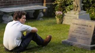 Georgie sitting by his father's grave on Georgie & Mandy's First Marriage Season 1 Episode 2