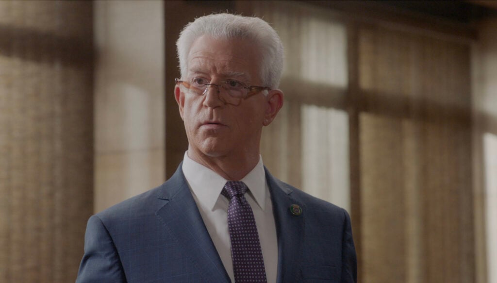 Garrett standing with his reading glasses on and looking upset on Blue Bloods Season 14 Episode 15