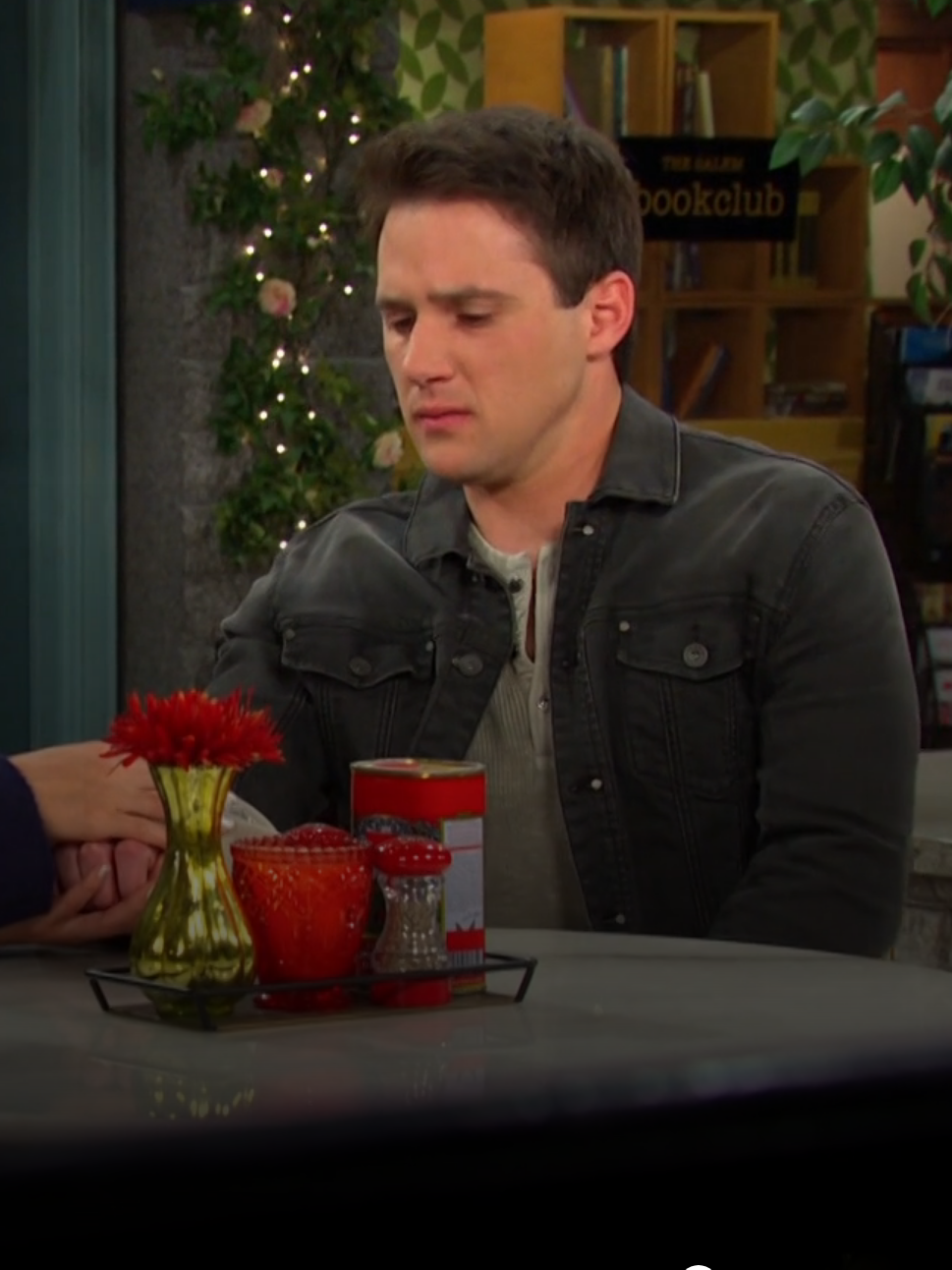 Gabi sitting with her hand over JJ's at a table in the Square on Days of Our Lives during the week of 11-19-24